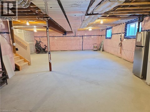 A spacious unfinished room with a staircase and a window.