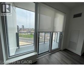 A spacious room with wooden flooring and large windows.