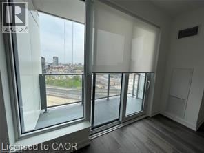 A spacious room with wooden flooring and large windows.