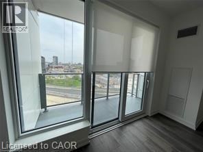 A spacious room with wooden flooring and large windows.
