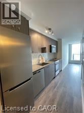 A modern kitchen with stainless steel appliances and wooden flooring.