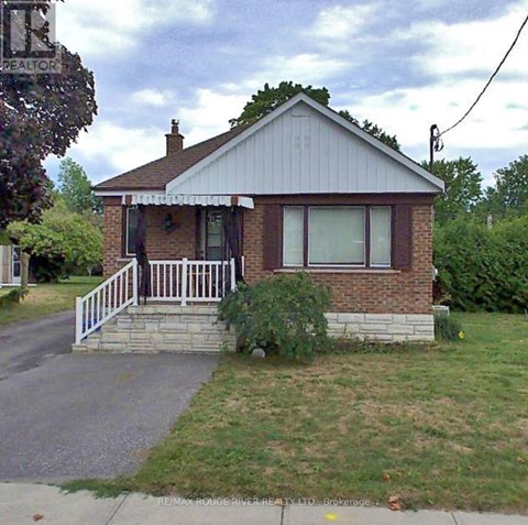 A house with a porch and a sign that says RE/MAX Rouge River Realty LTD. Brokerage.