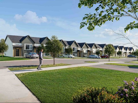 A man is walking in a residential area with houses on both sides.