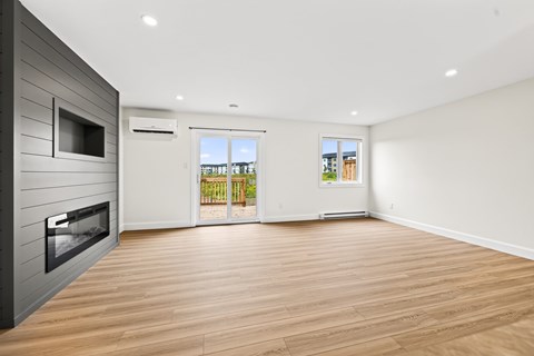 A spacious room with wooden flooring and a television on the wall.