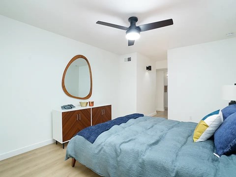 A bedroom with a bed, dresser, and mirror.