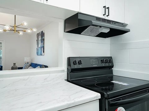 A black stove top oven with a white stove top and a black range hood above it.