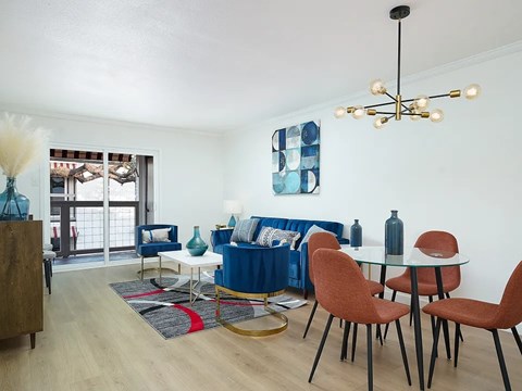 A living room with a blue couch and a glass table.