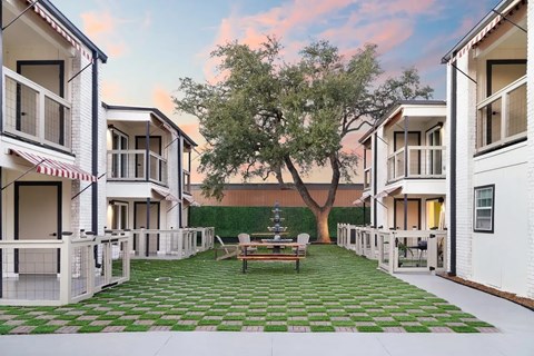 A courtyard with a tree and a bench surrounded by white buildings.