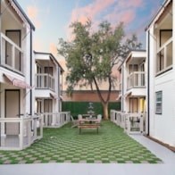 A courtyard with a bench and a tree between two buildings.