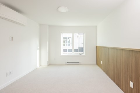 A large empty room with a window and a door.