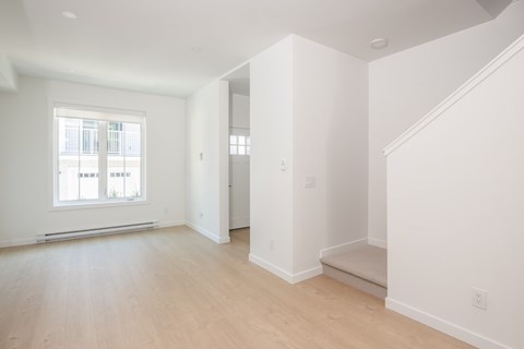 A large empty room with wooden floors and white walls.