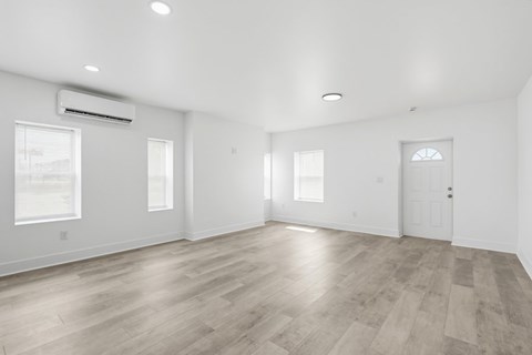A spacious room with wooden flooring and white walls.