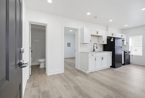 A kitchen with white cabinets and a black fridge.