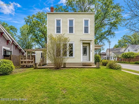 A two-story house with a front porch and a tree in front.