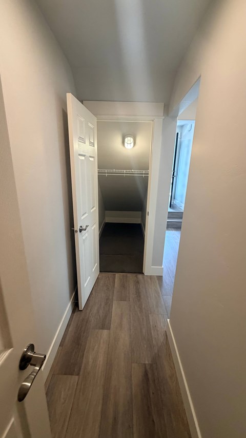 A hallway with a wooden floor and white walls.