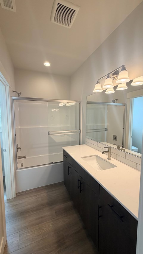 A bathroom with a sink, mirror, and a glass shower door.