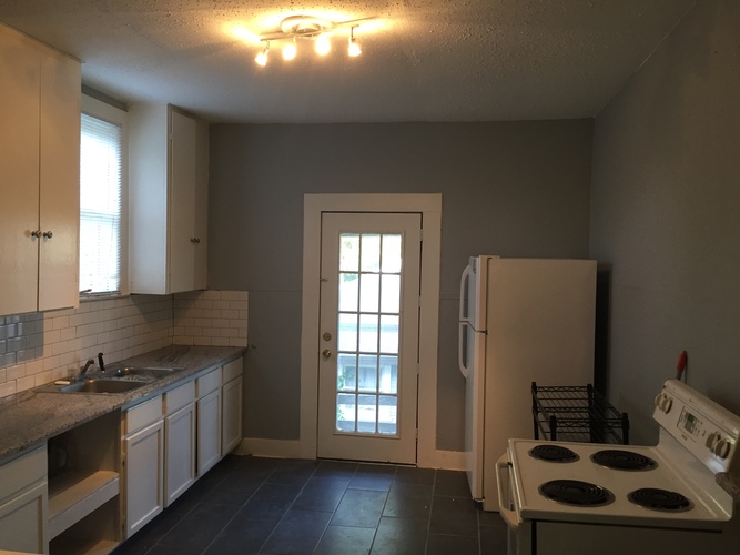 A kitchen with a white stove and a door leading outside.