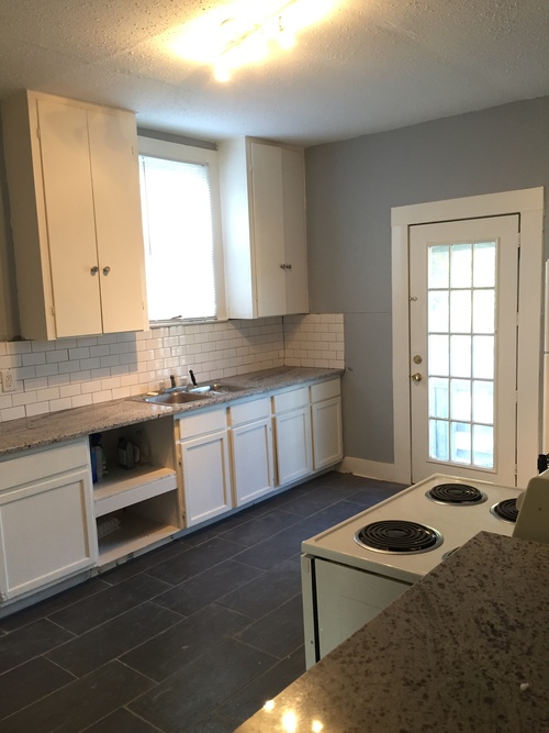 A kitchen with white cabinets and a white door.