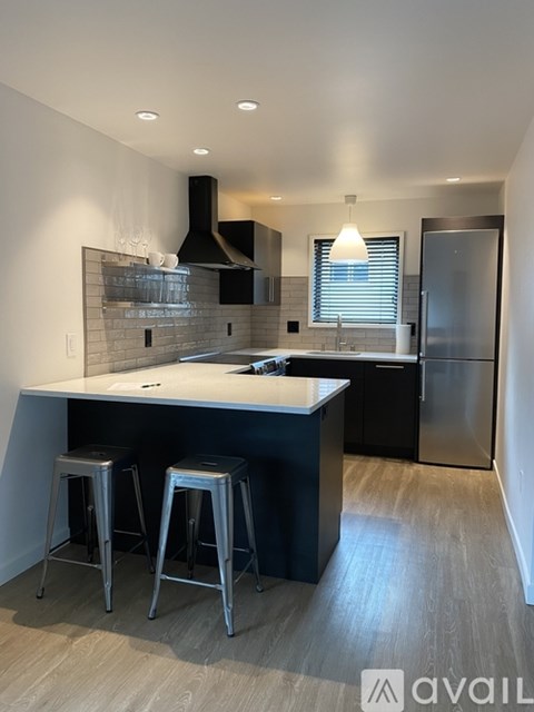 A modern kitchen with a white island and black stools.