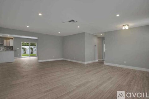 A spacious room with wooden flooring and white walls is available for rent.