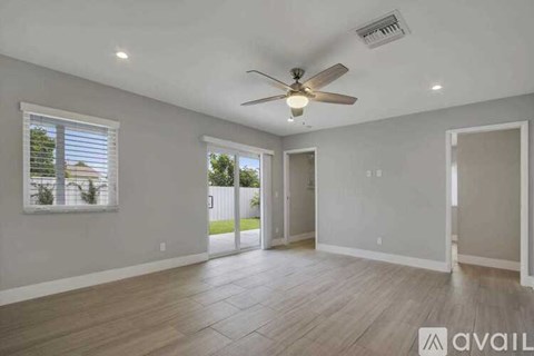 A spacious room with a ceiling fan and sliding glass doors leading to a backyard.