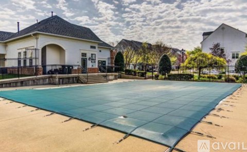 A large outdoor swimming pool surrounded by a fence and a building in the background.