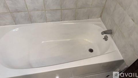 A white bathtub with a silver faucet is in a bathroom with white tiled walls.