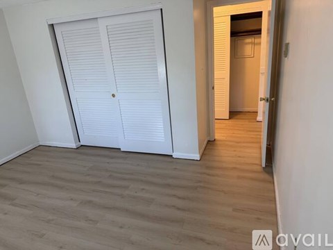 A room with a white door and wooden floor.