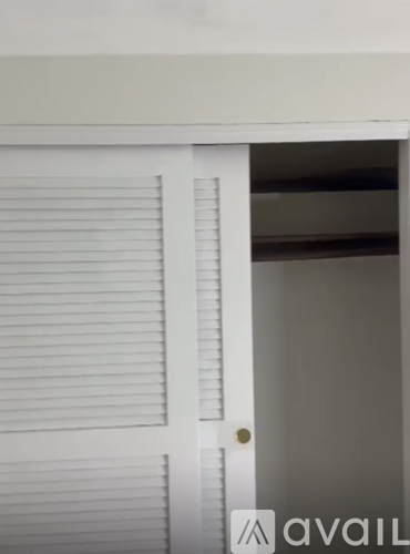 A white door with a gold handle and a window with white blinds.