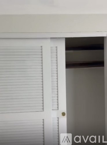 A white door with a gold handle and a window with white blinds.