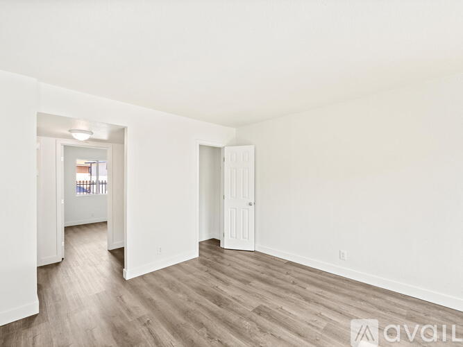 A spacious room with white walls and wooden flooring.