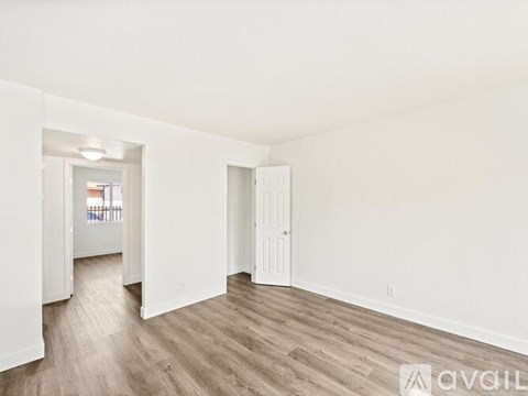 A spacious room with white walls and wooden flooring.