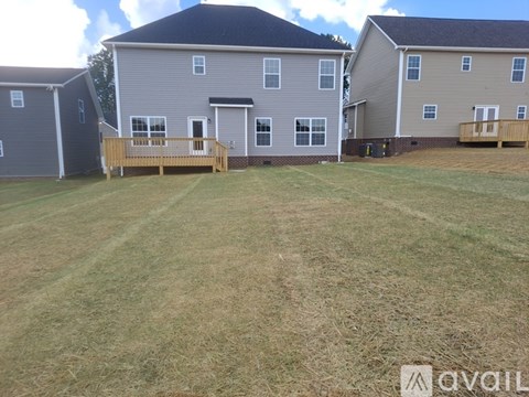 A grassy field with two houses and a wooden deck in the foreground.