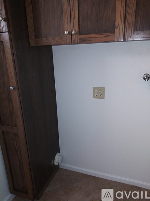 A brown wooden cabinet with a white wall and a light switch.