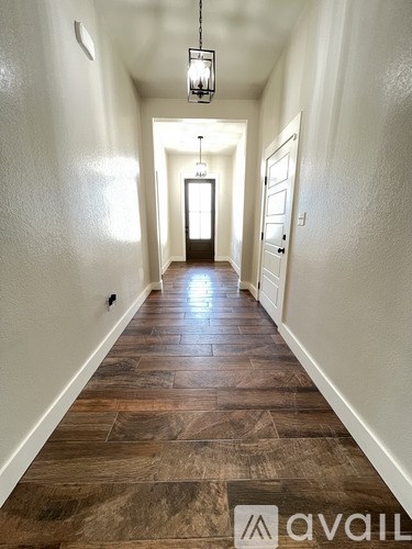 A hallway with wooden floors and a light hanging from the ceiling.