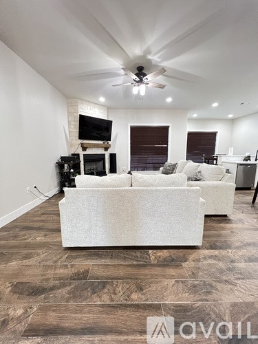 A living room with a white couch and a television on a stand.