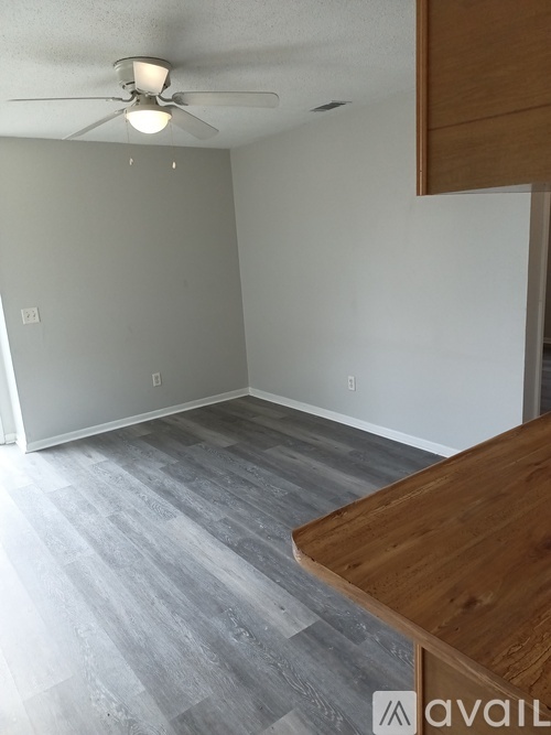 A room with a wooden table and grey carpet.