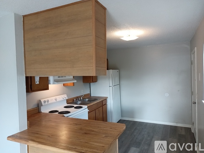 A kitchen with a white stove and wooden cabinets.