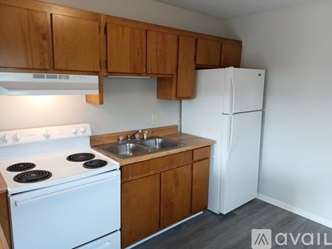 A kitchen with a white stove, wooden cabinets, and a white refrigerator.