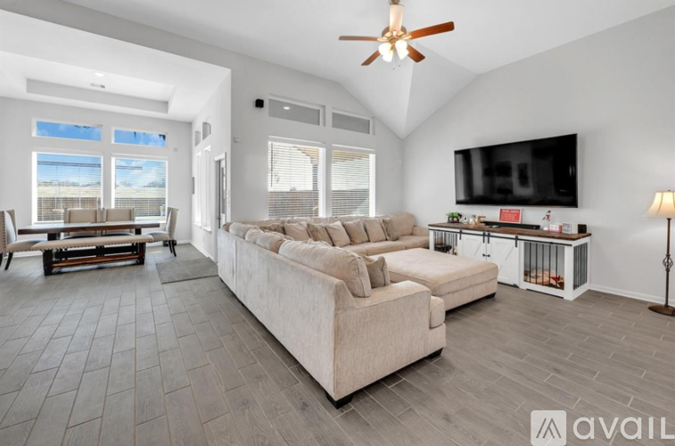 A spacious living room with a large sectional sofa and a flat-screen TV mounted on the wall.