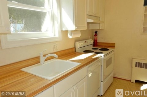 A kitchen with a white stove top oven and a white sink.