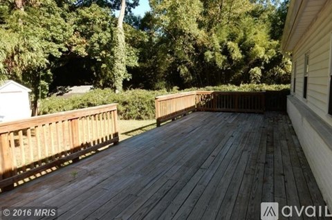 A wooden deck with a railing and trees in the background.