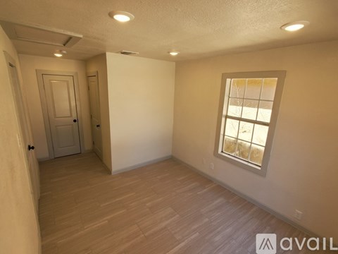 A room with a door and a window with a view of a fence.