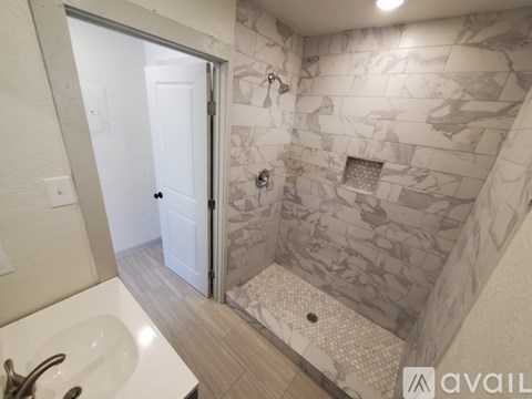 A bathroom with a marble tile shower and a white sink.