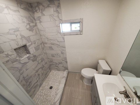 A bathroom with a marble tile shower and a toilet.