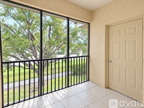 A balcony with a black railing and a view of a tree and a road.