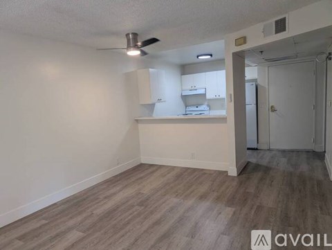A room with a fan and a door leading to another room.
