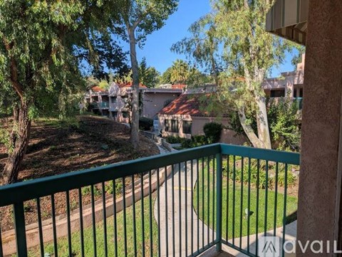 A balcony view of a green lawn and trees.