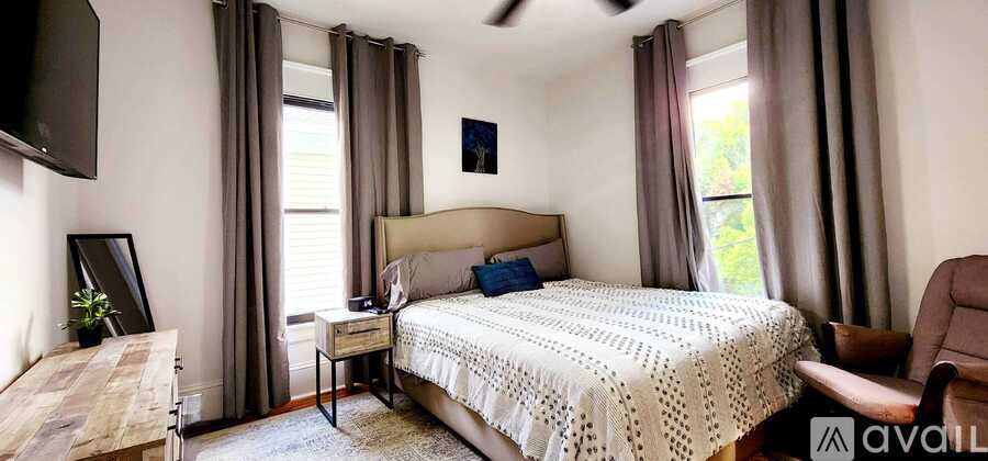 A bedroom with a large bed and a television mounted on the wall.