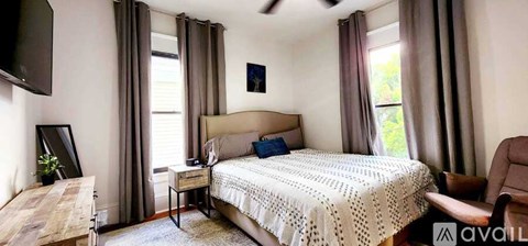 A bedroom with a large bed and a television mounted on the wall.